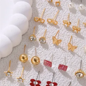 Nahaufnahme von verschiedenen goldenen Ohrsteckern mit Schleifen, Strass und süßen Motiven.
