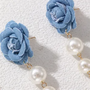 Nahaufnahme von eleganten blauen Jeansstoff Rosen Ohrringen mit langen Perlen Quasten.