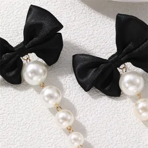 Detailaufnahme von Ohrringen mit schwarzen Schleifen und Perlen für einen eleganten Look.