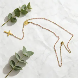 Stainless steel gold-toned rosary long necklace with pink beads and cross pendant detail.