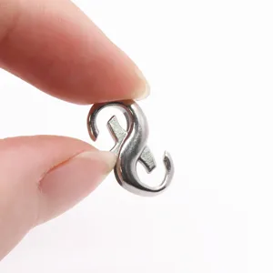 Primer plano detallado de hebilla de metal en forma de S, conector para joyería DIY.