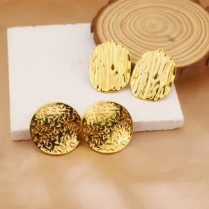 Close-up detail of vintage gold-plated stainless steel textured geometric earrings and charms.