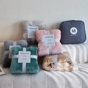Groep zachte microplush flanellen dekens in meerdere kleuren op een getextureerde bank
