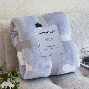 Gevouwen lichtblauwe micropluche flanellen deken met wolkenpatroon en productlabel