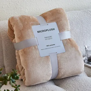 Detail van beige micropluche deken met grijs lint en polyester onderhoudslabel