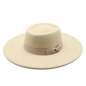 Close-up detail of the elegant beige felt wide-brim fedora hat with a delicate bow ribbon.
