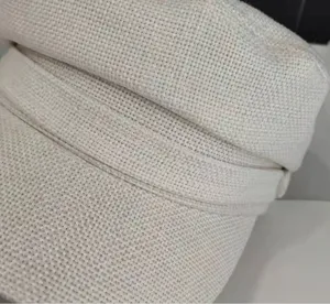 Closeup detail of casual beige linen cotton women captain hat woven texture fabric fashion.