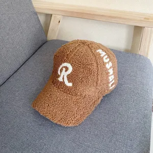 Close-up of brown sherpa baseball cap with white embroidered letter R and side text detail.