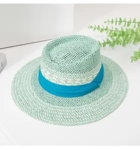Close-up view of the mint green woven straw hat featuring a vibrant blue ribbon band detail.