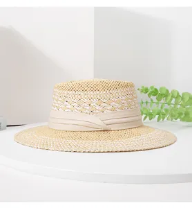 Detailed view of the woven straw boater hat with beige ribbon trim and unique pattern.