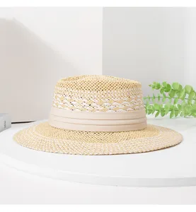 Detailed close-up of a woven straw hat with a stylish flat top and elegant ribbon trim.