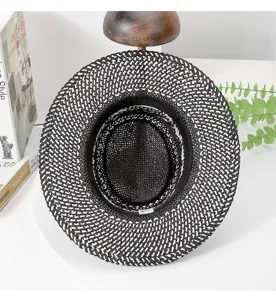 Straw hat detail view showcasing black white woven pattern, wide brim and dented top.
