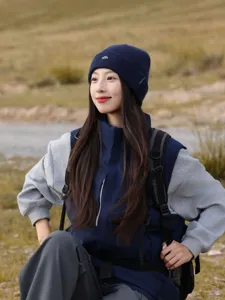 Detailed shot of a stylish navy blue knit beanie with embroidered mountain logo for women outdoor.