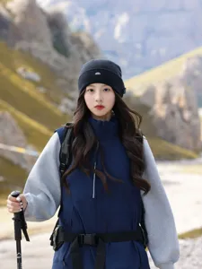 Close-up detail of the black knitted beanie with embroidered mountain logo for outdoor hiking.