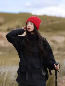 Outdoor detail shot of a stylish red knitted beanie hat worn in mountain hiking scene.