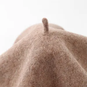 Close-up detail of soft wool beret top crown texture, cozy autumn winter hat accessory.