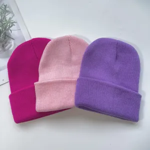 Detail view of colorful knit beanie hats in magenta, pink and purple for cold weather.