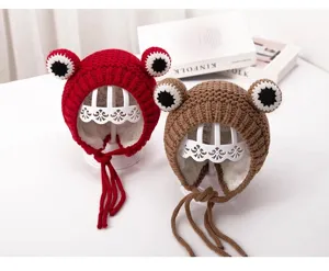 Detailed closeup of cute toddler knit frog hat with fleece lining and braided earflap ties.