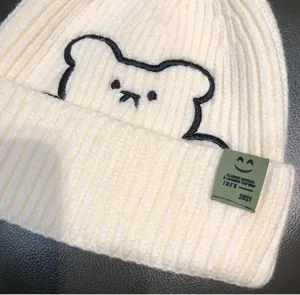 Beanie hat winter warm knitted cute bear embroidery detail close up beige soft fabric