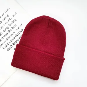 Close-up detail of burgundy knitted beanie ribbed texture autumn winter warm hat display