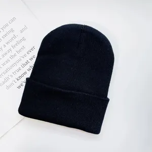 Close-up detail of a solid black knitted beanie hat, showcasing winter warm soft wool texture.