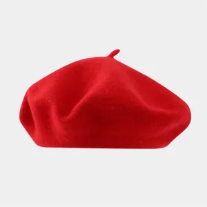 Close-up detail shot of a classic red wool beret, showing soft felt texture and neat stitch.