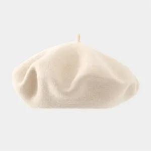 Close-up detail of the soft beige wool beret, showcasing smooth texture and classic top stem.