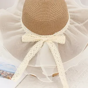 Close-up detail of women straw sun hat with large mesh brim and elegant white lace bow ribbon.