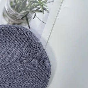 Grey knitted beanie hat detail, soft acrylic winter warm children plain skull cap closeup.