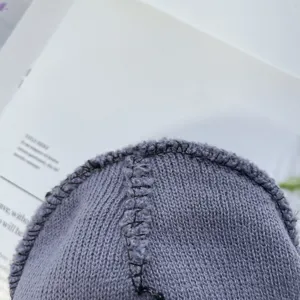 Detailed close-up of children's grey-purple knitted beanie hat, soft acrylic knit texture.