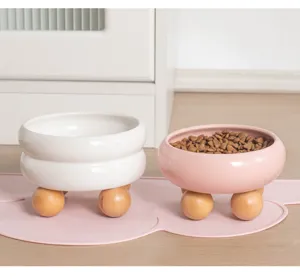 Vista dettagliata di ciotole per animali domestici in ceramica con piedini in legno su tappeto.