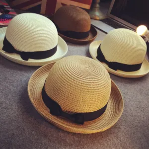Detailed view of summer straw dome hats with black ribbon bows, sun protection beach wear.
