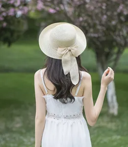 Detailed back view of women summer straw hat featuring a large bow, beach sun protection.