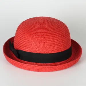 Close-up detail of red straw bowler hat with black bow, summer sun protection beach hat.