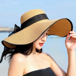 Detail view of the elegant wide-brim straw hat with black bow and edge, perfect for beach.