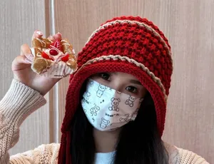 Close-up detail of the red handmade knitted woolen hat with tassels and warm ear flaps.