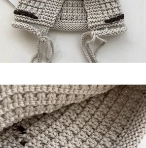 Detailed closeup of a handmade knitted wool earflap beanie hat with tassel ties and texture.