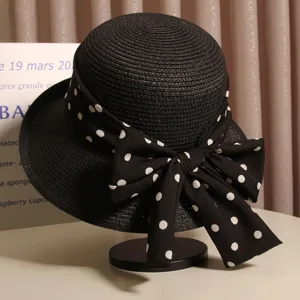 Exquisite detail view of French elegant black straw hat featuring rolled brim and polka dot bow.