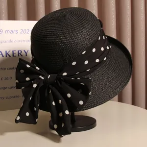 Detail shot of black straw hat featuring a chic polka dot bow and rolled brim for summer beach.