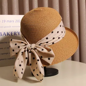 Close-up detail of summer straw bucket hat with elegant polka dot bow ribbon, stylish resort sun hat.