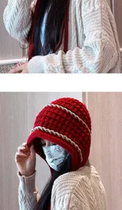Detail view of handmade knitted tassel beanie hat in red with beige stripes, warm winter hat.