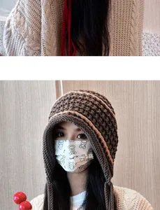 Detail view of the handmade knitted hat showing cozy texture, ear flaps, and winter warmth.