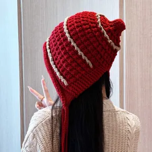 Handmade red knit beanie hat with cute earflaps and tassels for warm autumn and winter fashion.