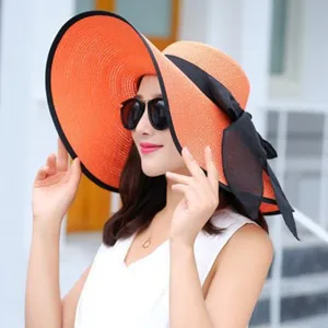 Elegant wide-brim straw sun hat for women with black bow and contrasting rim for beach.