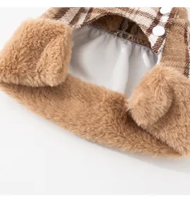 Dettaglio abito invernale caldo per animali a quadri marroni con morbido peluche e bottoni.