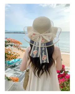 Cappello di paglia estivo a tesa larga con fiocco ricamato a fiori, perfetto per le vacanze.