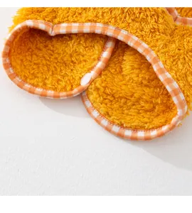 Vue détaillée de vêtements pour animaux en polaire jaune avec bordure écossaise et bouton.