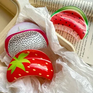 Detail view of fruit print hair claw clips in strawberry and watermelon patterns