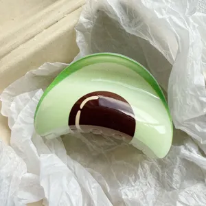 Close-up of a glossy avocado fruit shaped hair claw clip nestled in white tissue paper