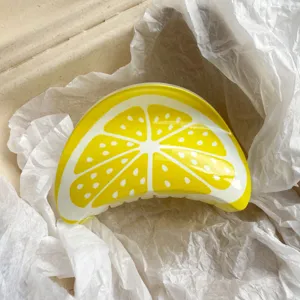 Close-up of a vibrant yellow lemon-shaped resin hair claw clip inside a package box